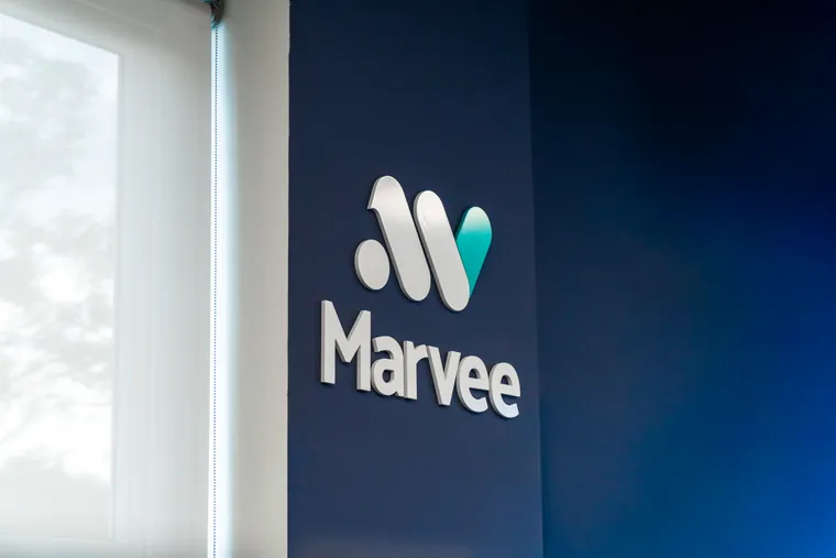 Logo da Marvee em relevo na parede azul da sede, ao lado de uma janela
